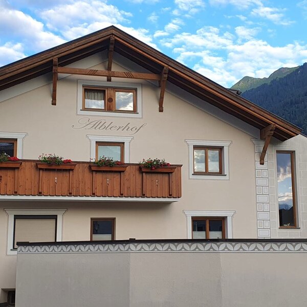 L'esterno del Bauernhof Alblerhof, con architettura tradizionale, un balcone in legno con fioriere e vista sulle montagne.