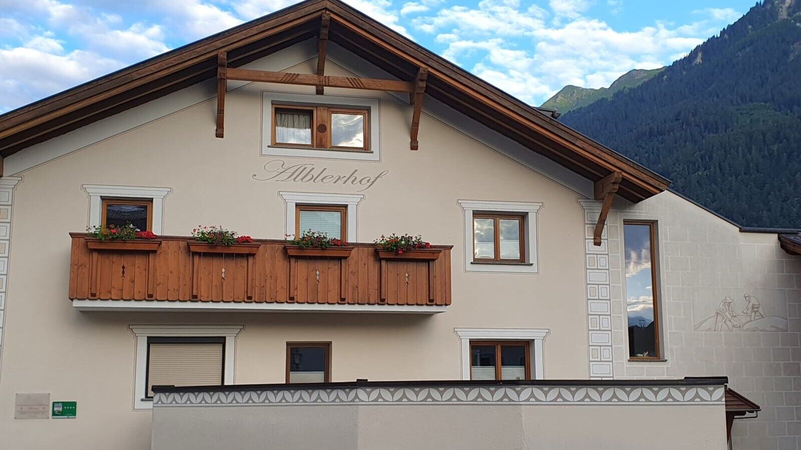 L'esterno del Bauernhof Alblerhof, con architettura tradizionale, un balcone in legno con fioriere e vista sulle montagne.