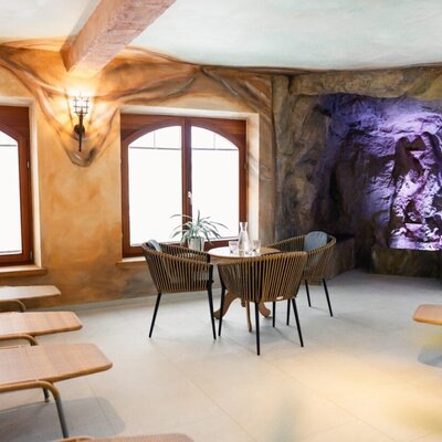 Area relax nella zona benessere con lettini, sedute e la cosiddetta "Kunerngrotte" sullo sfondo.
