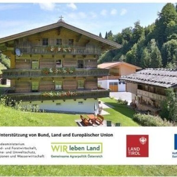 L'accogliente agriturismo circondato da verdi prati di montagna, caratterizzato da tradizionali balconi in legno e un curato giardino.