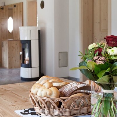 L'invitante zona pranzo dell'appartamento con un tavolo rustico in legno, un fresco mazzo di fiori e un accogliente camino sullo sfondo.