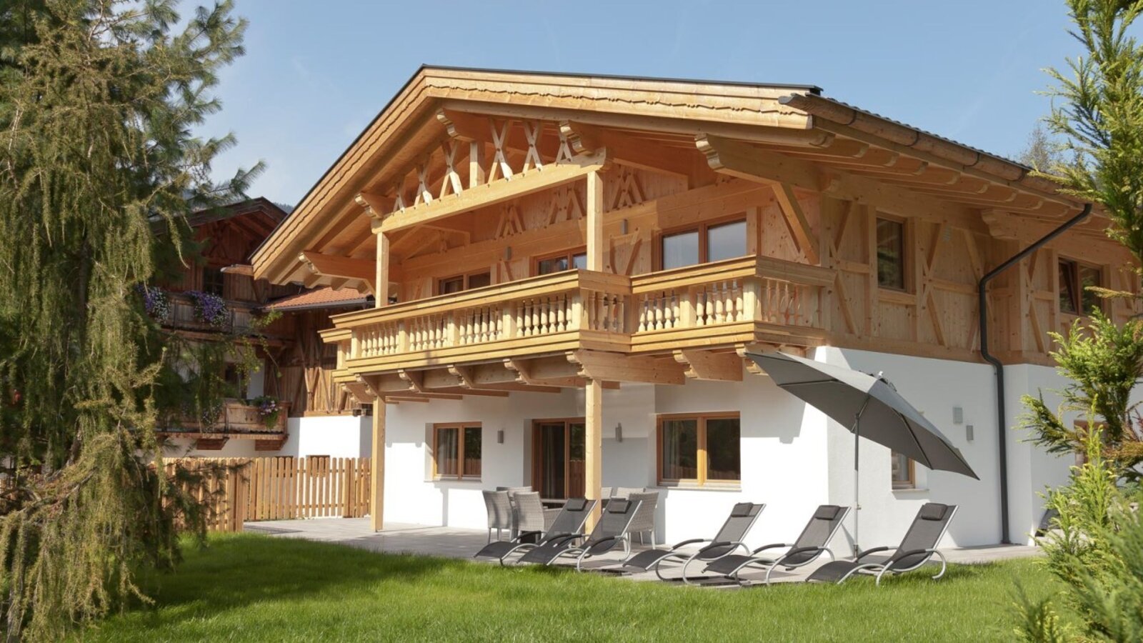 Gli accoglienti appartamenti con facciata in legno, terrazza soleggiata e comodi lettini nel giardino verdeggiante.