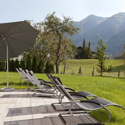 L'invitante giardino degli appartamenti con comodi lettini, un ombrellone e una magnifica vista sulle montagne circostanti.