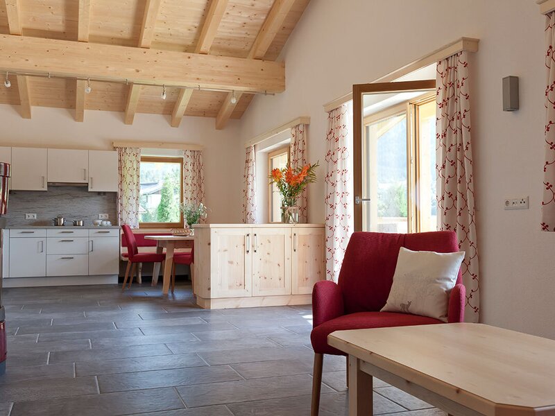 Un appartamento spazioso con soffitti in legno chiaro, un accogliente caminetto, una cucina moderna e accesso diretto al balcone.