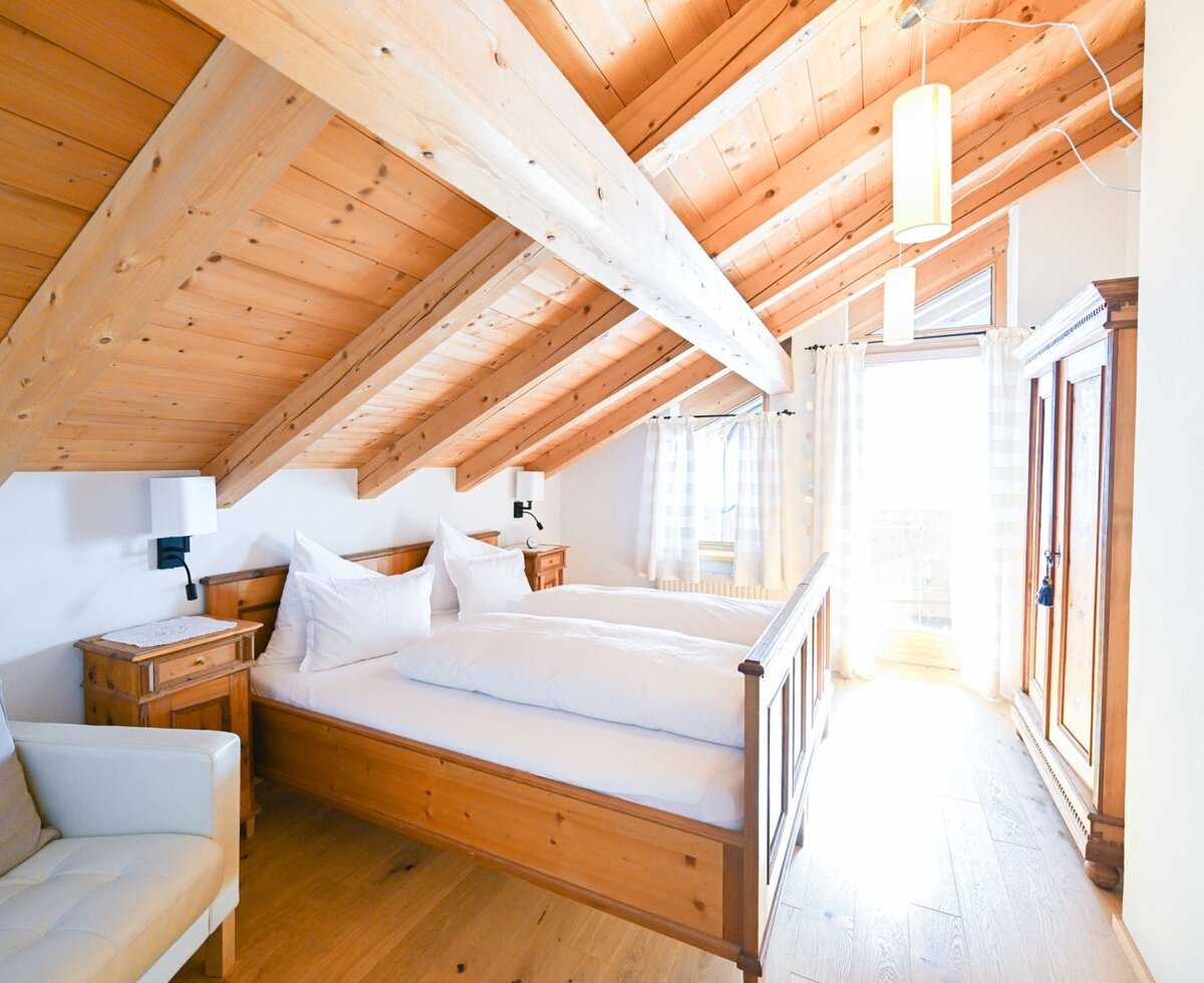 Camera da letto nell'appartamento dell'agriturismo, con letto matrimoniale in legno di pino, soffitto con travi a vista, armadio e angolo salotto.