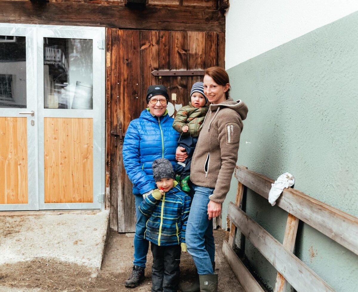 La famiglia ospitante del Bauernhof Bergerhof con bambini davanti a un edificio della fattoria.