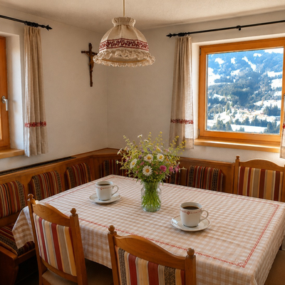 Accogliente zona pranzo dell'alm con una tradizionale panca ad angolo in legno e vista panoramica sulle montagne innevate.