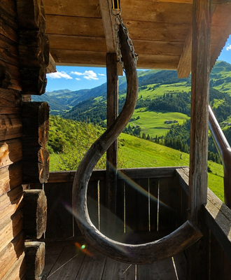 L'accogliente balcone della malga con un'originale altalena in legno e una splendida vista sulle verdi vallate.