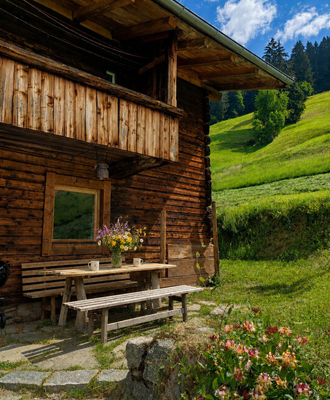 Un'accogliente area salotto all'aperto davanti alla rustica Alm, circondata da prati lussureggianti.