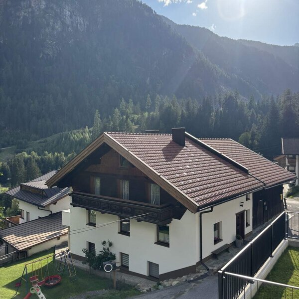 L'accogliente condominio di appartamenti sullo sfondo di un suggestivo panorama montano, con un piccolo parco giochi in giardino.