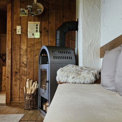 Un'accogliente area giorno nell'agriturismo con una stufa a legna rustica e una confortevole panca.