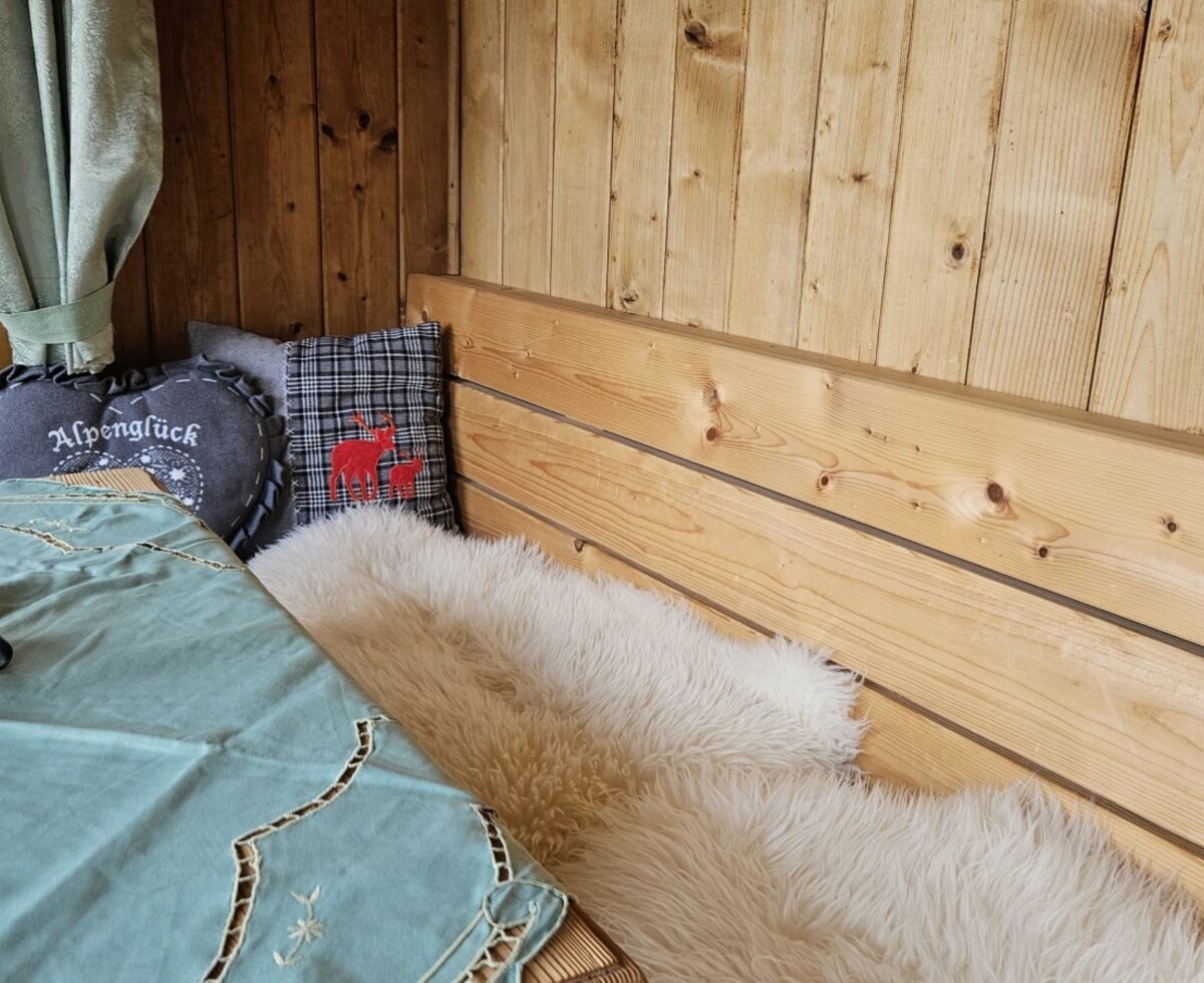Accogliente angolo salotto nella casa vacanze con rustici pannelli in legno, morbide pelli di pecora e cuscini decorativi.