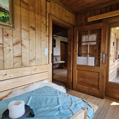Un'accogliente camera con pareti in legno tradizionali e accesso diretto al balcone soleggiato.