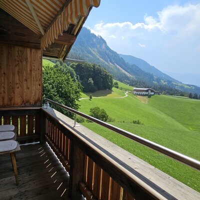 Invitante balcone con accoglienti sedie in legno e una vista grandiosa sulle verdi colline e sulla valle.