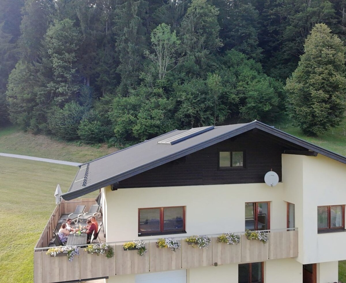 L'accogliente agriturismo con un ampio balcone fiorito, circondato da prati verdi e boschi.