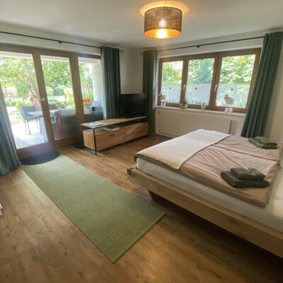 Una camera da letto luminosa e accogliente nell'agriturismo, con letto matrimoniale, TV a schermo piatto e accesso diretto alla terrazza soleggiata.