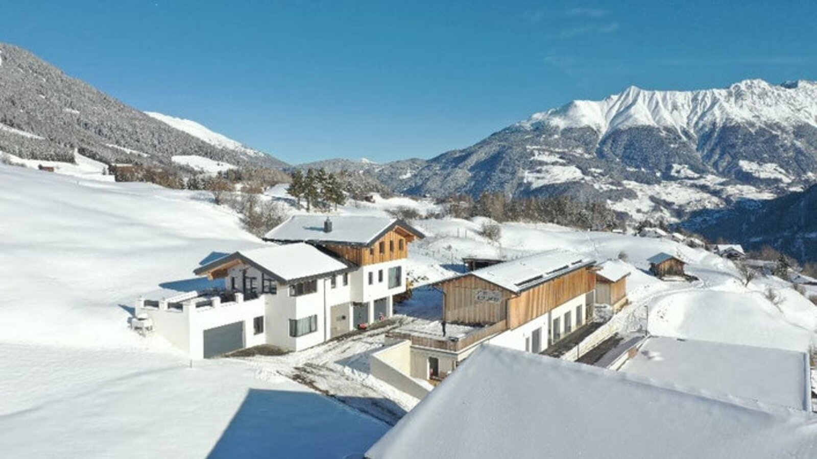 Gli appartamenti in un paesaggio montano invernale, circondati da pendii e montagne innevate.