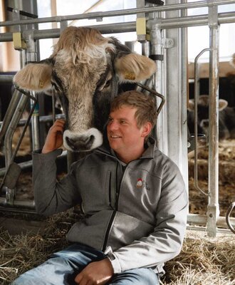 Il contadino accarezza una mucca nella stalla.