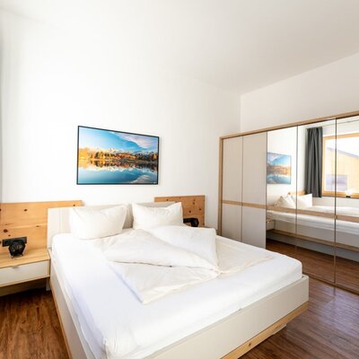 Camera da letto della Ferienwohnung con letto matrimoniale, comodini e armadio a specchio.