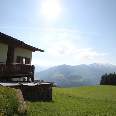 Flecklhütte con balcone, situata su un prato verde con vista sulle montagne.