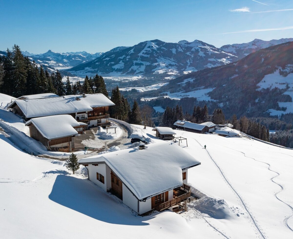 La Flecklhütte, composta da diversi edifici coperti di neve, immersa in un paesaggio montano invernale.