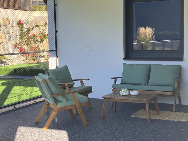 Un'invitante terrazza coperta del bed and breakfast con comodi mobili in legno e cuscini verdi per rilassarsi.