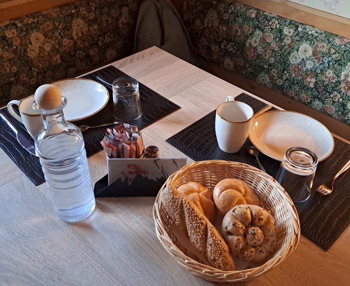 Un'accogliente tavola apparecchiata per la colazione nell'agriturismo, con panini freschi e una confortevole panca ad angolo.