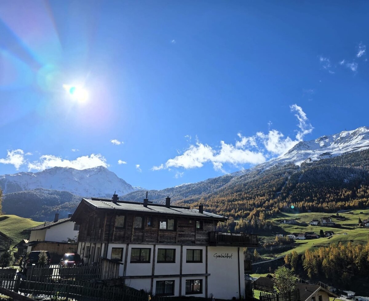 Il Bauernhof con vista sulle montagne innevate e sulla valle sotto un cielo azzurro.