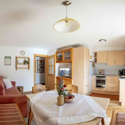 Zona giorno e cucina dell'agriturismo con tavolo da pranzo, divano e angolo cottura completamente attrezzato.