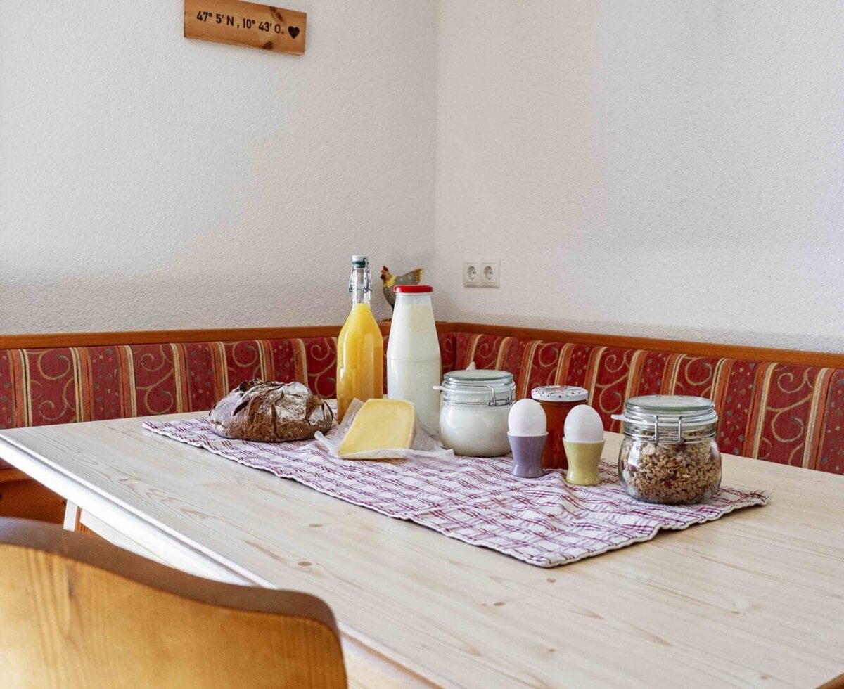 Tavolo da colazione nell'agriturismo con pane fresco, formaggio, latte, succo, uova e muesli.