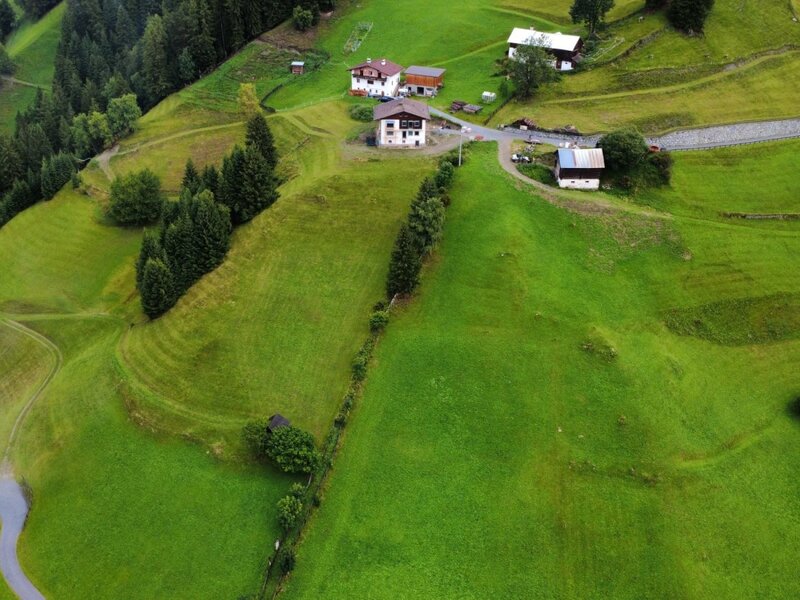 Una vista aerea degli appartamenti immersi tra lussureggianti pendii montani e fitti boschi di pini.