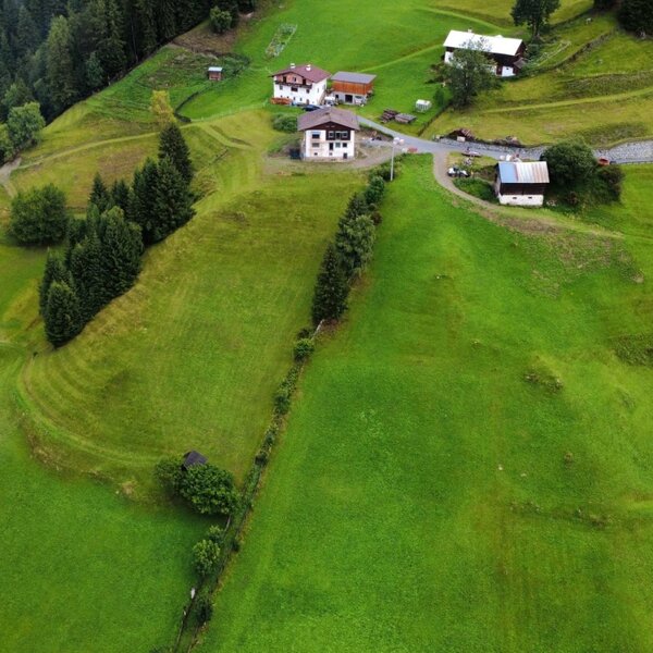 Una vista aerea degli appartamenti immersi tra lussureggianti pendii montani e fitti boschi di pini.