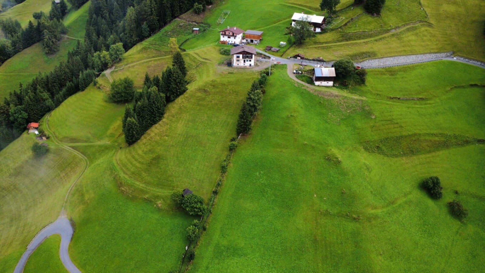 Una vista aerea degli appartamenti immersi tra lussureggianti pendii montani e fitti boschi di pini.
