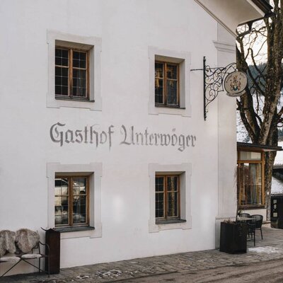 Esterno del Gasthof Unterwöger con insegna, finestre e un'area salotto all'aperto.