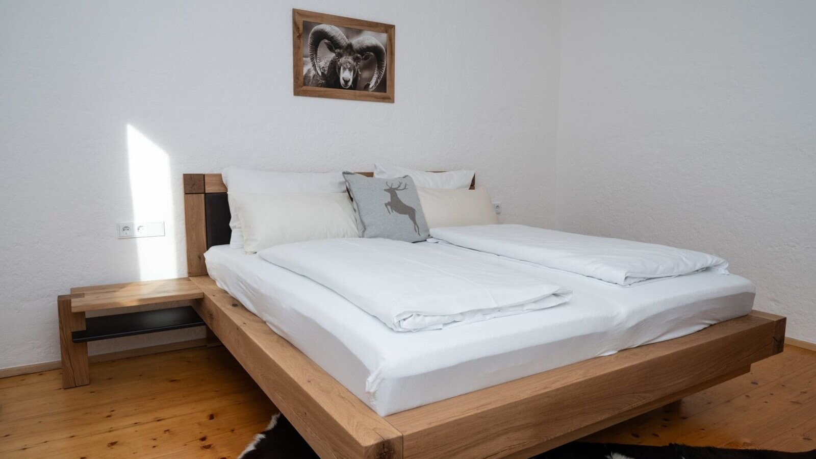Camera da letto nell'appartamento con un letto matrimoniale in legno, comodino integrato e pavimento in legno.