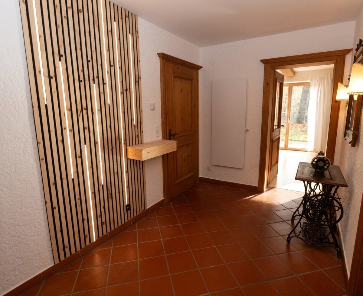 Area d'ingresso dell'Apartment con moderna parete a doghe in legno, illuminazione integrata e piastrelle in terracotta.