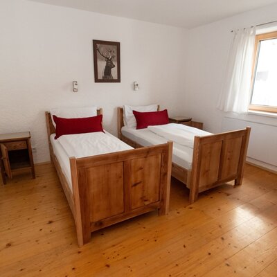 Camera da letto nel Bed and Breakfast con due letti singoli, pavimenti in legno e una finestra.