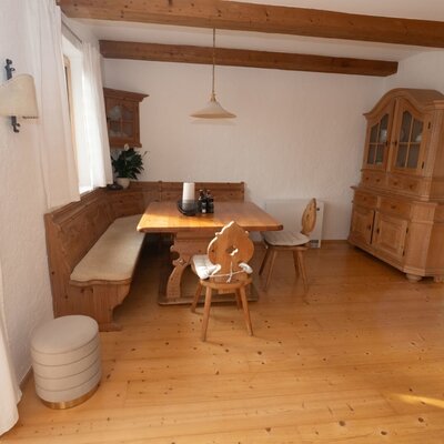 La zona pranzo nell'Apartment presenta un tavolo in legno, una panca ad angolo e sedie tradizionali in legno sotto travi a vista.