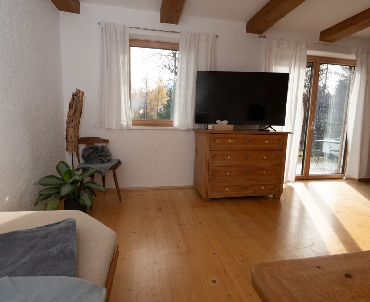 Soggiorno dell'appartamento con TV, cassettiera in legno e accesso diretto alla terrazza.