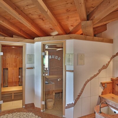 L'area sauna nell'agriturismo, con una cabina a infrarossi, una sauna tradizionale e una panca in legno con lavandino.