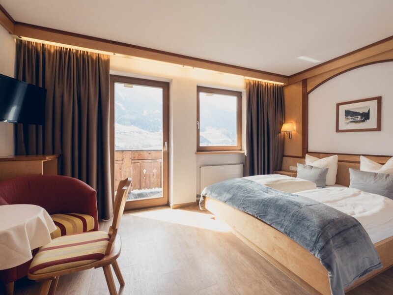 Camera confort con letto matrimoniale, armadio, zona soggiorno, TV a schermo piatto, cassaforte e balcone con vista