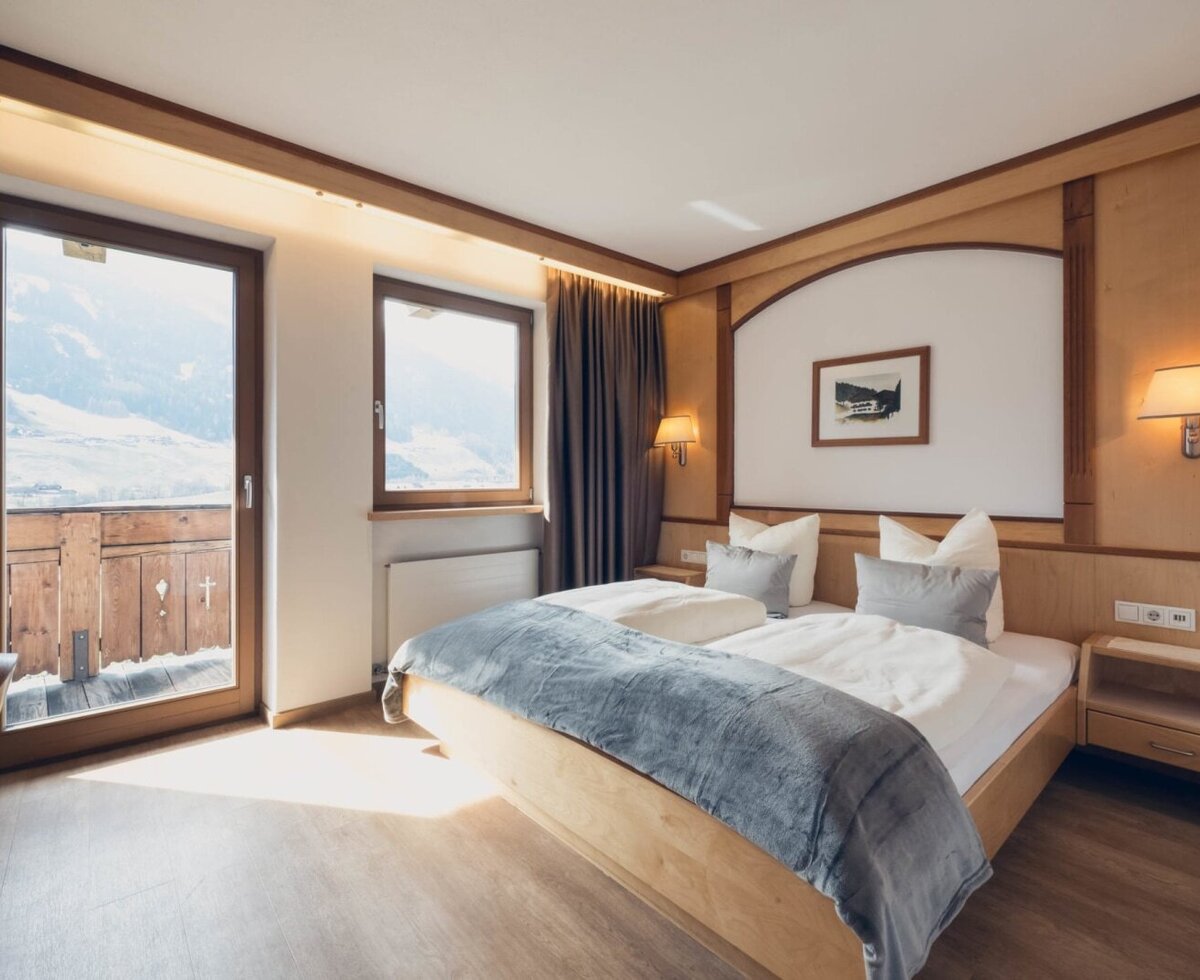Camera confort con letto matrimoniale, armadio, zona soggiorno, TV a schermo piatto, cassaforte e balcone con vista