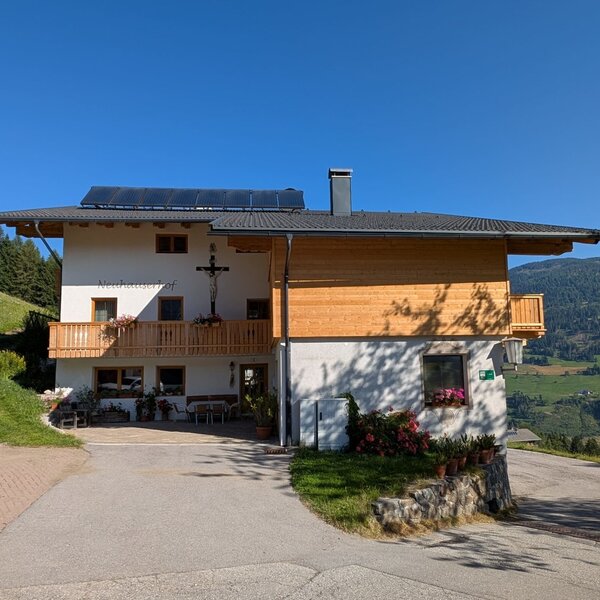 Il maso con balconi, pannelli solari sul tetto e una terrazza con vista sulle montagne.