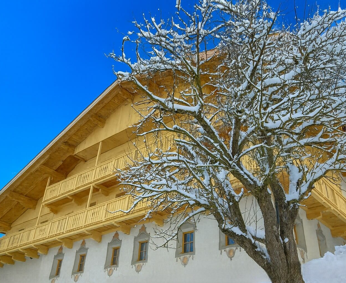 L'agriturismo innevato con balconi in legno e facciata tradizionale in inverno.