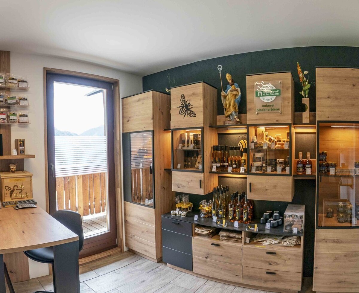 Area vendita nel Bauernhof con scaffali in legno, prodotti locali e accesso al balcone.
