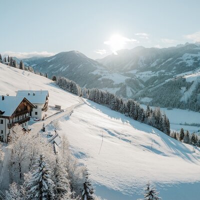 Il maso in un paesaggio montano innevato sotto il sole splendente.