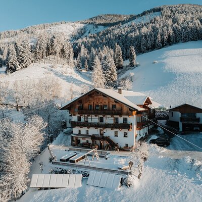 Il maso in un paesaggio montano innevato con un parco giochi per bambini.
