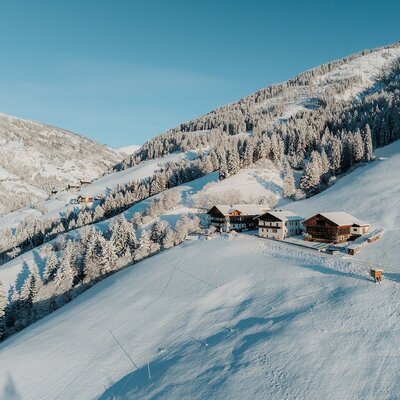 L'esterno del maso in un paesaggio montano innevato, circondato da foreste.