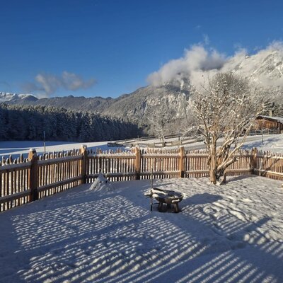 Il giardino innevato dell'appartamento “d´kloane Mühle” con braciere e vista sul paesaggio montano circostante.