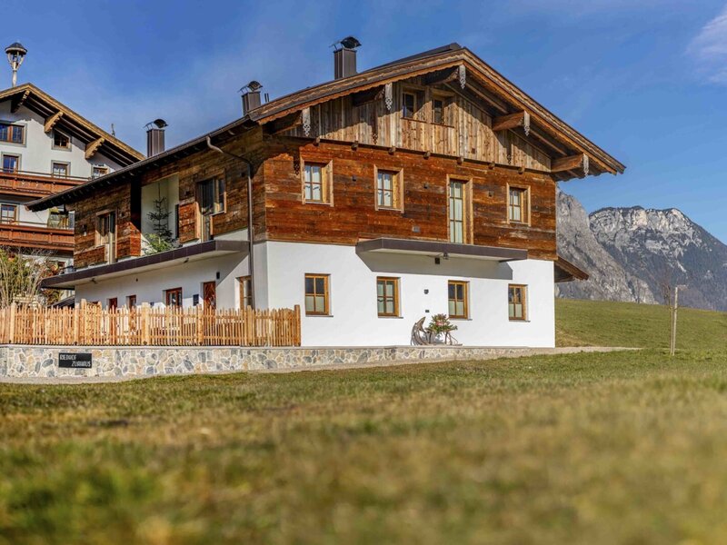 Vista esterna dell'edificio Zuahaus sul Bauernhof, con facciata tradizionale in legno, piano terra bianco e vista sulle montagne.